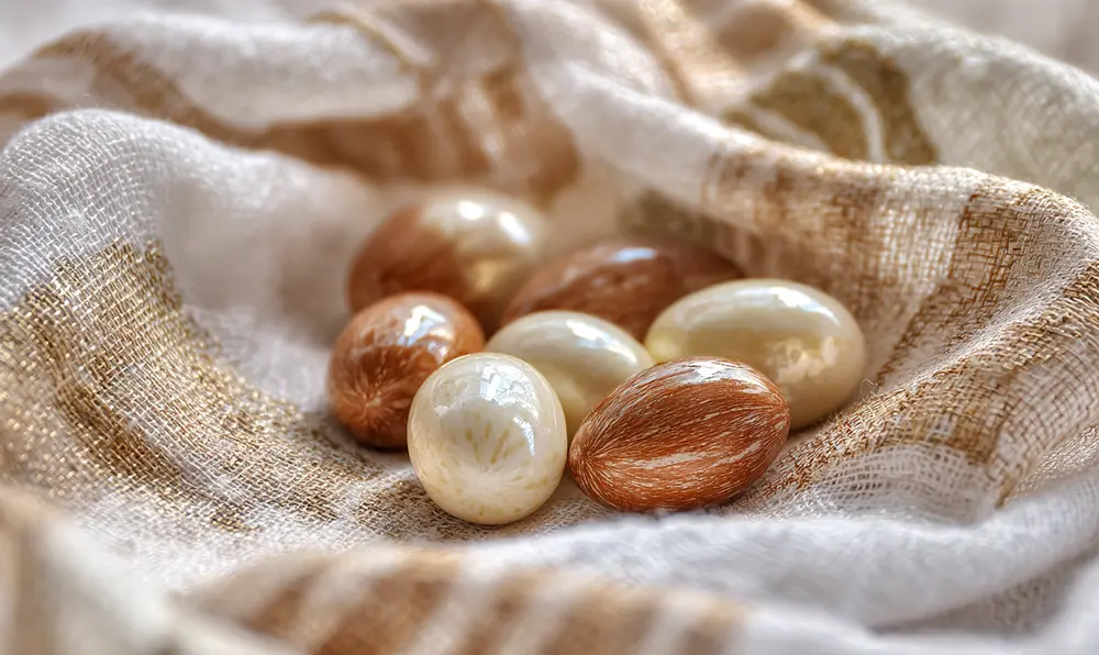 Dragées aux amandes Avola brillantes dans un ballotin, représentant les cinq vœux de la tradition (fertilité, bonheur, prospérité, santé, partage)