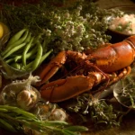 Table provençale remplie d’aliments commençant par H : haricots, homard, herbes et huiles parfumées