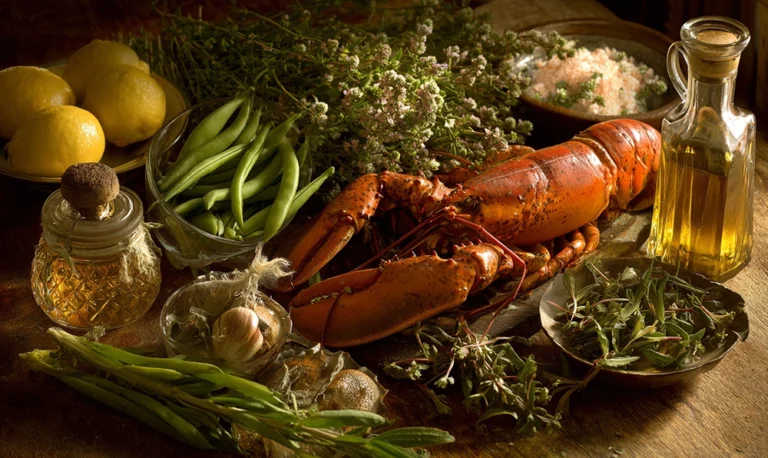 Table provençale remplie d’aliments commençant par H : haricots, homard, herbes et huiles parfumées