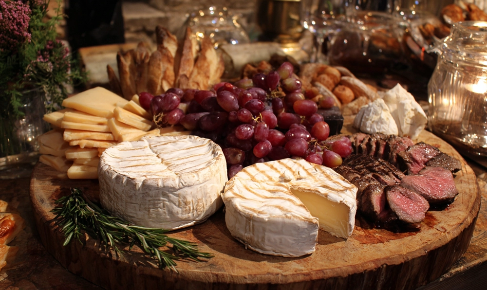 Assortiment d’aliments en V sur une table rustique : vacherin, vitelotte, vanille et vin rouge