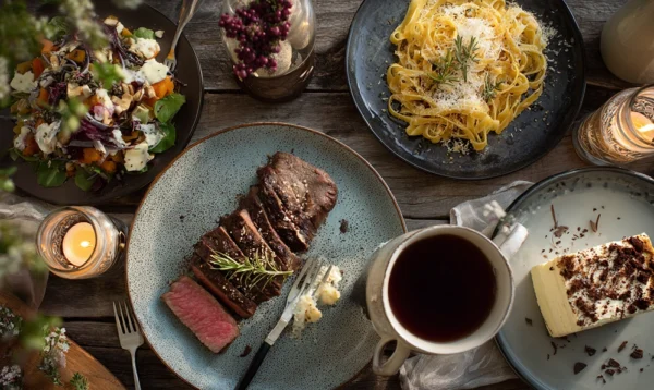 Table conviviale dressée avec tagliatelles, tournedos et tiramisu