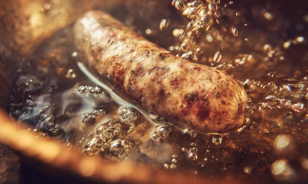 Gros plan sur une saucisse de Morteau cuite, dorée et juteuse, sortie d’eau chaude
