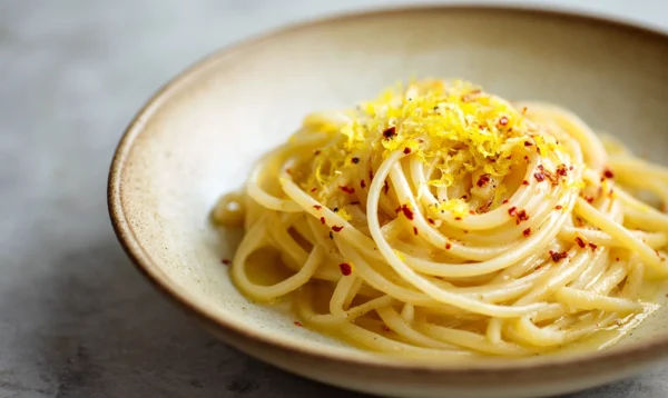 Plat de linguines à la poutargue avec citron et piment sur fond clair