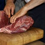 Gros plpan sur les main d'un boucher découpant de la viande premium à maturation