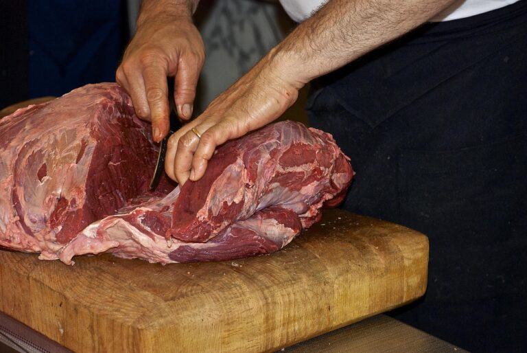 Gros plpan sur les main d'un boucher découpant de la viande premium à maturation