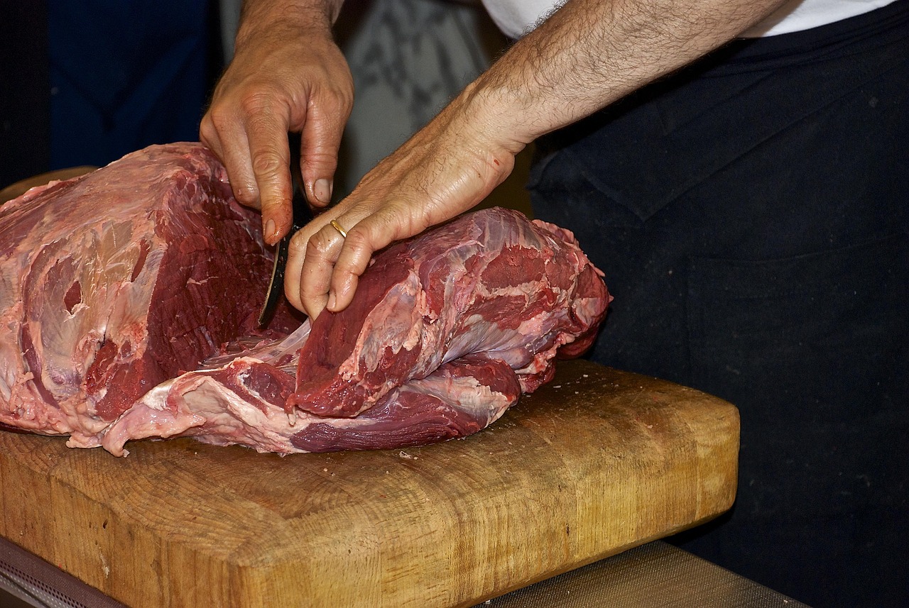 Gros plpan sur les main d'un boucher découpant de la viande premium à maturation