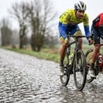 Deux cyclistes professionnels en plein effort sur un secteur pavé humide lors de la course Paris-Roubaix.