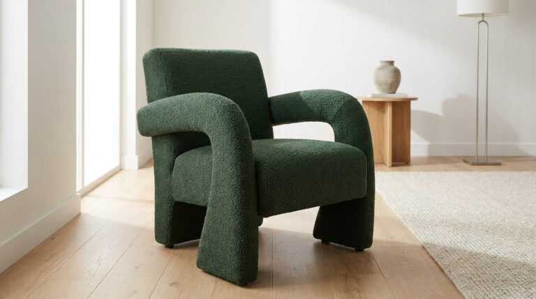 Fauteuil moderne au design sculptural recouvert d'un tissu bouclé vert forêt, posé sur un parquet en bois clair.