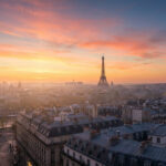Vue panoramique des toits de Paris avec la tour Eiffel sous un ciel coloré au lever du soleil.